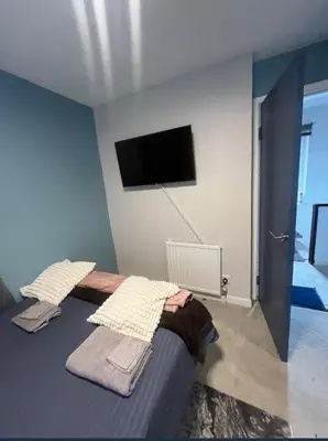 a bedroom with a bed with a flat screen tv on the wall at Stylish 3 bedroom house in Glasgow