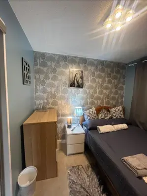 a bedroom with a bed with a night stand and a table at Stylish 3 bedroom house in Glasgow