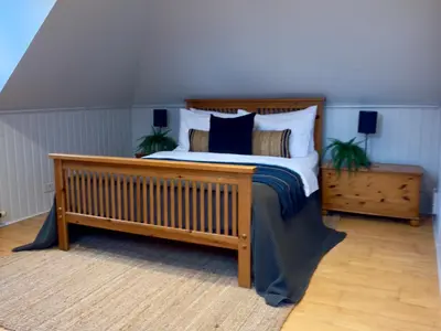 a bedroom with a wooden bed with pillows at Upstairs at Carlingford in Newton Mearns