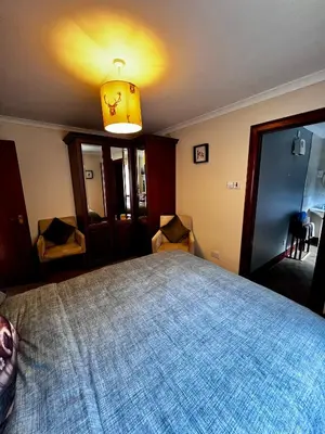 a bedroom with a large bed with a blue blanket at The Cottage at Craigavon House in Ballachulish