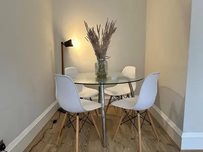 a dining room with a glass table and white chairs at Appin Apartments - Welcome to a delightful and cozy one bedroom flat in Glasgow
