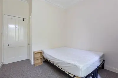 a white bedroom with a bed and a door at 3 Bedrooms Flat in Central Edinburgh New Town , Lothian Road in Edinburgh