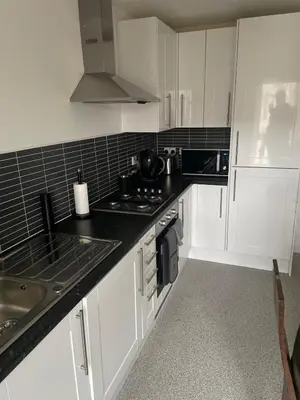 a kitchen with white cabinets and a black counter top at Maison 109 Suite - Modern City Apartment in Glasgow