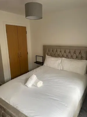 a white bed with a roll of toilet paper on it at Maison 109 Suite - Modern City Apartment in Glasgow