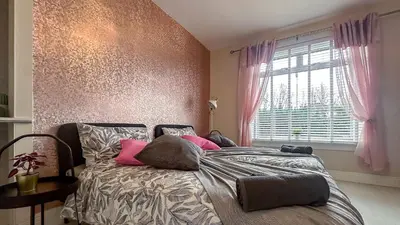 a bedroom with a bed with pink pillows and a window at Quite and new Glasgow house, Commore Drive in Drumchapel