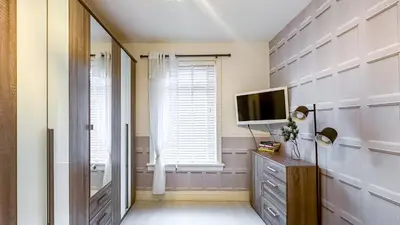 a room with a television and a dresser and a window at Quite and new Glasgow house, Commore Drive in Drumchapel