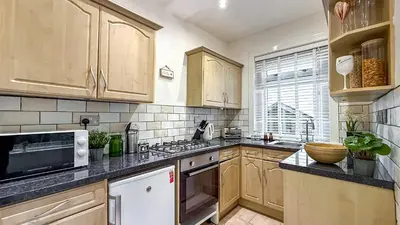 a kitchen with wooden cabinets and a microwave at Quite and new Glasgow house, Commore Drive in Drumchapel