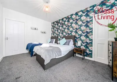 a bedroom with two beds and a floral wall at Lady Wilson Apartment by Klass Living Airdrie in Airdrie