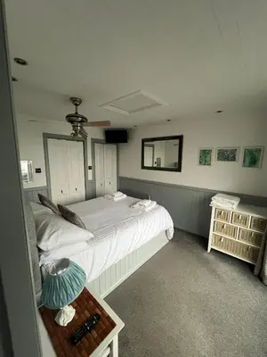 a bedroom with two beds and a table and a mirror at Misty Isles Cottage- Ellenabeich, Easdale, Isle of Seil