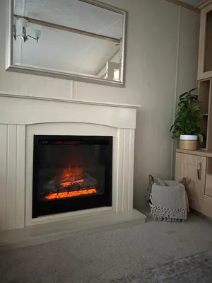 a living room with a fireplace with a mirror at Glen-coo in Auchterarder