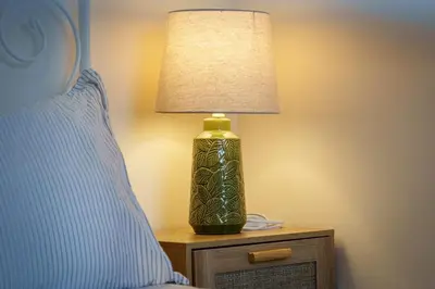 a green lamp sitting on a table next to a bed at 2BR Apartment with Parking Near Southside and Queens Park in Mansewood
