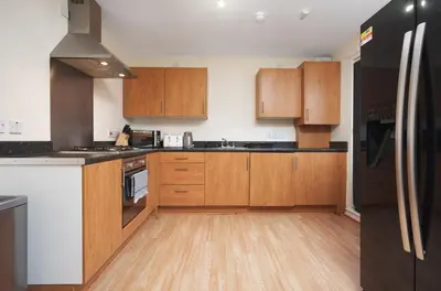 a kitchen with wooden cabinets and a black refrigerator at 2BR Apartment with Parking Near Southside and Queens Park in Mansewood