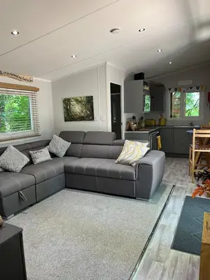 a living room with a couch and a kitchen at Ty Cwtch Cabin - secluded woodland cabin & covered hot tub in Moffat