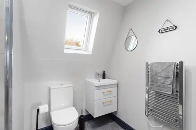 a white bathroom with a toilet and a window at Large Edinburgh Studio - Close to City Centre, Murrayfield and Airport in Edinburgh