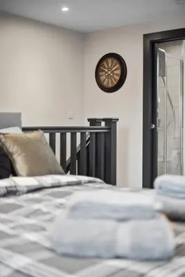 a bedroom with a bed and a clock on the wall at Large Edinburgh Studio - Close to City Centre, Murrayfield and Airport in Edinburgh