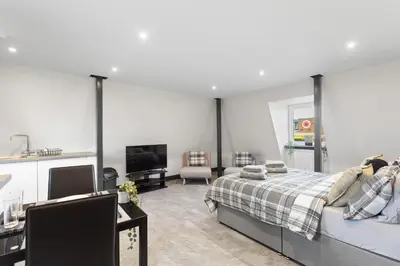 a bedroom with a bed and a living room with a tv at Large Edinburgh Studio - Close to City Centre, Murrayfield and Airport in Edinburgh