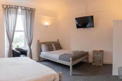a bedroom with two beds and a tv on the wall at The Woodside in Cowdenbeath
