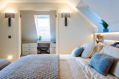 a bedroom with a large white bed with blue pillows at The Shore House in Lamlash