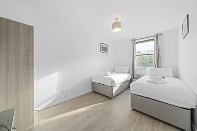 a white bedroom with two beds and a window at Lauriston 1 Bedroom Apartment - Edinburgh in Edinburgh