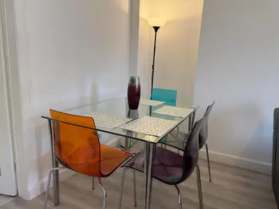 a glass table with two chairs and a vase on it at Glasgow 2 Bedroom Apartment Access To City Centre in Gartcosh