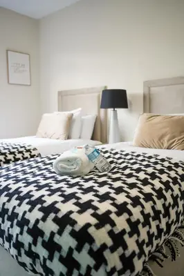 a bed with a black and white blanket on it at Stobhill Apartment in Glasgow
