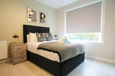 a bedroom with a bed and a window with a window shade at Stobhill Apartment in Glasgow