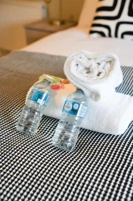 two bottles of water and a towel on a bed at Stobhill Apartment in Glasgow