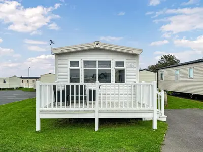 a white house with a porch on the grass at Coastal Bay View in Ayr