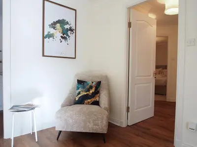 a living room with a chair and a table at Fettes - Homely 2BD in Quiet Development in Edinburgh
