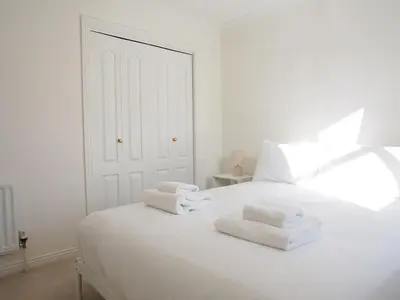 a white bedroom with white towels on a white bed at Fettes - Homely 2BD in Quiet Development in Edinburgh