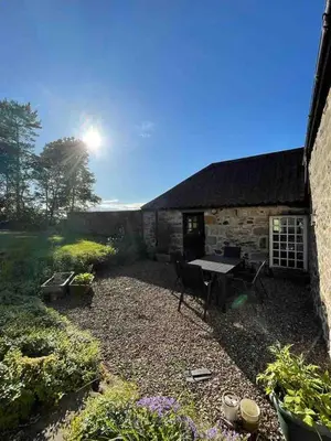 a backyard with a table and a stone building at Linlithgow cottage close to Edinburgh in Linlithgow
