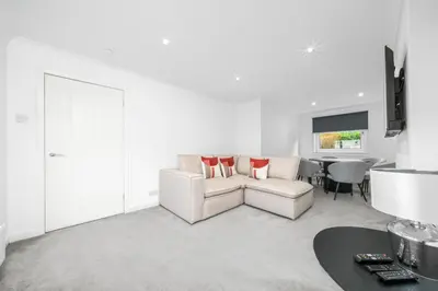 a white living room with a couch and a table at The Elphin Escape in East Kilbride