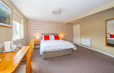 a bedroom with a bed with red pillows and a desk at The Clachan Hotel, Lochearnhead in Lochearnhead