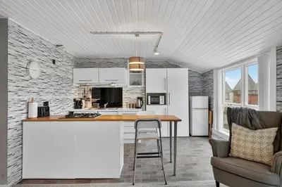 a kitchen with white cabinets and a table and a chair at Coastal Charm: Modern Retreat by Seafront in Largs