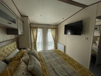 a small bedroom with a bed and a tv on the wall at Wemyss Bay Beaumont Elite in Skelmorlie