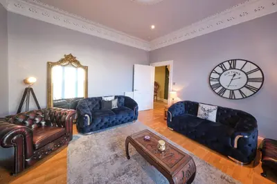 a living room with couches and a clock on the wall at Bruce on the Row-Historic Elegance near Edinburgh by Urban Haggis Stays in Dunfermline