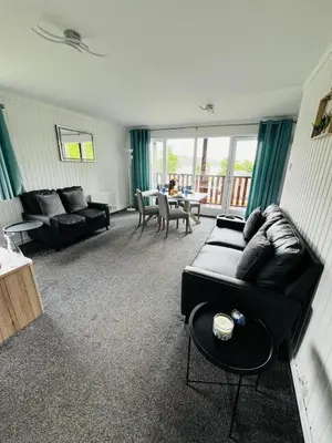 a living room with a black couch and a table at Tigh Na Sealladh in Dunoon