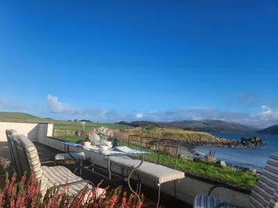 a patio with a table and chairs overlooking the water at 3 Bed in Kirkcolm oc-b34009 in Kirkcolm