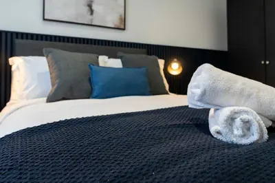 a bedroom with a large bed with towels on it at Linden House in Hamilton