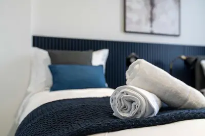 a bed with a rolled up towel on top of it at Linden House in Hamilton