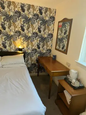 a hotel room with a bed and a desk and a wall at west park hotel PVT ltd in Clydebank