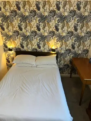 a bed with two pillows on it with a wall at west park hotel PVT ltd in Clydebank
