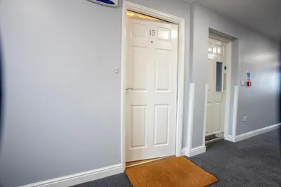 a hallway with a white door and a white refrigerator at Modern 2-Bed Flat, Sleeps 6, Near Gosforth in Moffat