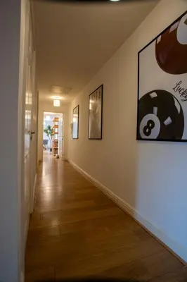 a hallway with paintings on the walls and wooden floors at Modern 2-Bed Flat, Sleeps 6, Near Gosforth in Moffat