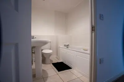 a white bathroom with a sink and a toilet at Modern 2-Bed Flat, Sleeps 6, Near Gosforth in Moffat
