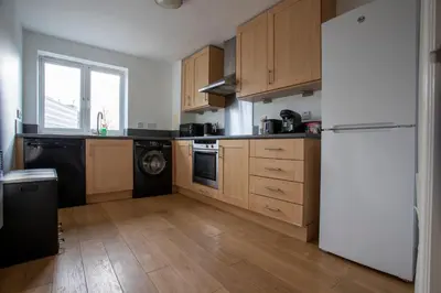 a kitchen with wooden cabinets and a black refrigerator at Modern 2-Bed Flat, Sleeps 6, Near Gosforth in Moffat