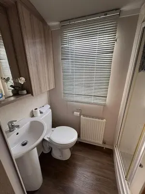 a bathroom with a white toilet and a sink at Luxury Seafront 3 Bedroom Caravan in Minishant