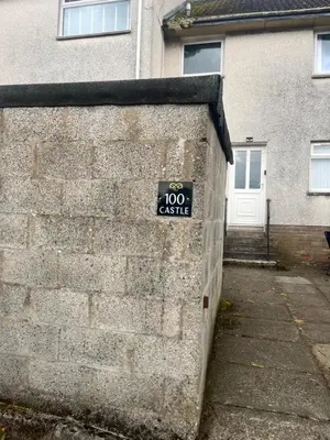 a sign on the side of a brick wall at 100 Castle in New Cumnock