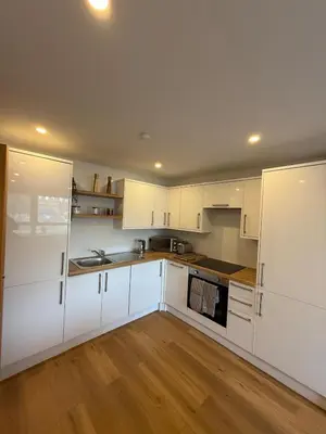 a white kitchen with white cabinets and wooden floors at Modern&Stylish city centre apartment with parking in Glasgow