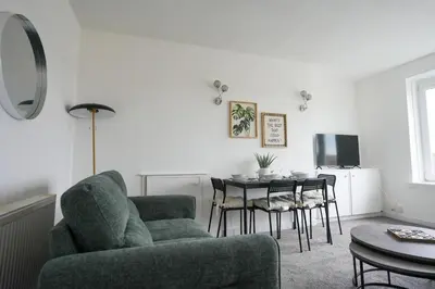 a living room with a couch and a table with chairs at 2 BDR Apartment By Caledonia Luxe Stays Short Lets & Serviced Accommodation Airdrie in Airdrie